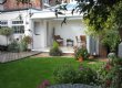 A view of a White Orangery with bi-fold doors stacked open
